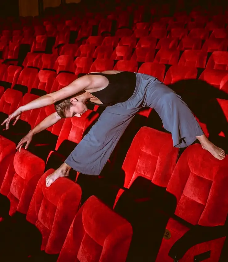 Dancer from an international dance competition posing with a contemporary dance movement while seated in a theater auditorium