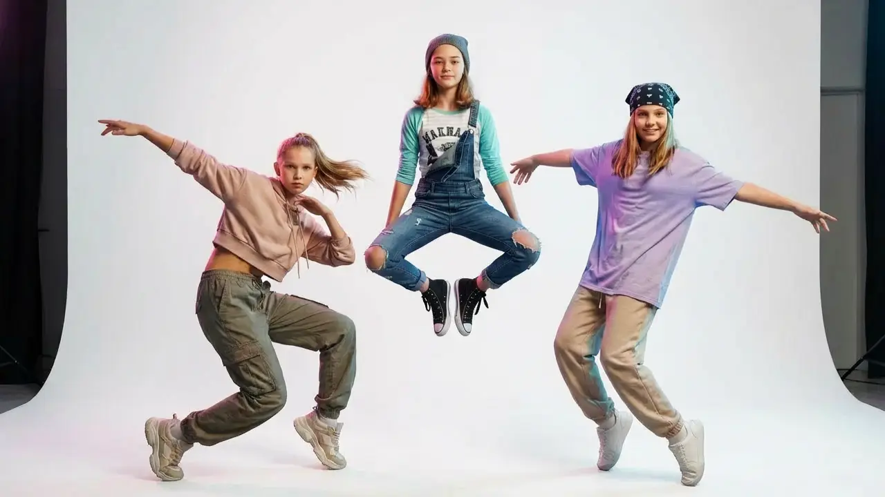 Urban Dance with children, boys, girls, and teenagers, three girls dancing, the center girl performing an urban jump in a photo studio